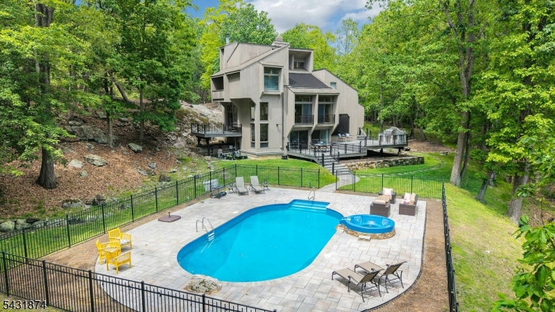 This extraordinary architectural masterpiece, nestled in a private woodland setting, offers over 4,000 square feet of sophisticated living surrounded by nature's beauty. An architect's dream built for his own family, this one-of-a-kind retreat showcases dramatic soaring vaulted ceilings and expansive floor-to-ceiling windows capturing breathtaking views of a scenic pond and the sparkling in-ground pool. Multiple decks, a screened porch, and private balcony provide seamless indoor-outdoor living. The stunning multi-level open floor plan offers a cascade of grand, light-filled living spaces that flow effortlessly together for everyday living and elegant entertaining. Meticulously maintained and lovingly renovated, the home features a spacious eat-in kitchen, beautifully updated baths, new flooring, new decks, newer roof, new furnace, new well pump, a whole-house generator, designer lighting, and upgraded electrical. The saltwater pool has new decking, fencing, solar and propane heaters, new pump and filter. You'll appreciate the convenient home gym! Offering complete privacy, timeless contemporary design, and a setting of unparalleled natural beauty, this remarkable residence is truly a once-in-a-lifetime opportunity. Far from it all, but near major highways, and just 35 miles to New York City. Boonton Township offers excellent schools, including the top-rated Mountain Lakes High School. Wouldn't you like to enjoy a pool this summer? Don't miss this very, very special home.