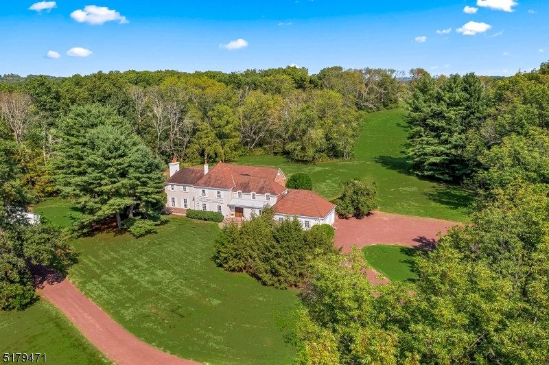 Impeccably renovated French Style home sited on 6 pastoral acres in Bedminster Hunt Country. Stunning light-filled Orangerie with barrel-valuted ceiling, 7 pairs of French doors & 2 crystal chandeliers. Gourmet  Eat-in kitchen with large center island, breakfast bar, pantry, high-end appliances and hardwood floor; Library with built-ins and fireplace. Bar with wine cooler, refrigerator, ice-maker and sink; Living Room with antique French corner cupboards and fireplace; Entry Foyer with antique doors & guest closet; Remodeled Powder Room with custom sink. On the second floor are the primary suite with luxurious bathroom featuring white marble, two additional en-suite bedrooms, balcony overlooking the Orangerie.  The Lower level offers the Family Room with raised-hearth brick fireplace, Recreation Room or possible use as fourth bedroom, and spacious Bathroom/Laundry Room.  Brick walks and patios highlight the grounds as well as boxwoods and flowering trees and shrubs. Generator. Plans ready for first-floor primary suite and pool. Generator services entire property. Carriage House/Cottage/Office. :  Great Room remodeled, new kitchen cabinets & appliances 2022, new tub/shower-second-floor Bathroom.  Perfect for an office, staff quarters and/or guest cottage. A Murphy Bed allows for the great room to be used as a second sleeping area. The great room has a stunning coffered ceiling. The mailing address uses Far Hills zip code 07931