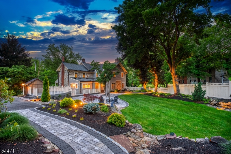 Stone Hill. Some homes are built. This one was kept. A meticulously restored 1827 stone residence in the countryside of Washington Township -- two centuries of craftsmanship, preserved and made effortlessly livable. The great room is unlike any you've stood in: 600 sq ft anchored by a 28-foot-wide sweep of exposed stone (the home's original 1827 exterior, now embraced within), a wood-burning fireplace, exposed beams, a marble wet bar, and the warm glow of wide-plank pumpkin pine. The home's history unfolds room by room. The dining room was the original 1827 kitchen, anchored by its brick fireplace and wood-burning stove. A wood Dutch door opens to a half-wraparound porch. A historic New Jersey winder staircase turns between floors. Restored pumpkin pine flows through most of both levels. Historic and livable are not a compromise here -- they are a pairing. 3,728 sq ft main residence, 4 bedrooms, 2.5 baths. A separate carriage house adds 500 sq ft of finished, heated flex space above a two-car garage. Two acres transformed into a private park, with 100 tons of natural rock integrated as sculpted landscape and a designer lighting system that sets stone, trees, and pathways aglow -- so that pulling into the driveway at night feels like coming home to a storybook. Set along a country road within the Asbury Historic District (National Register of Historic Places), across from a private golf course, just over an hour from NYC. Come see it at dusk, when it is at its most magical.