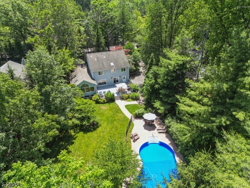 Set on over half an acre of level, landscaped property with a pool, this airy residence offers far more space than meets the eye. Elegantly understated, the home unfolds into a remarkably expansive interior designed for everyday living and entertaining. Its welcoming vestibule opens through inviting French doors to a generous fireside living room with bay window views, and an adjoining formal dining room bathed in natural light courtesy of floor-to-ceiling windows. The updated eat-in kitchen was designed for gathering, complete with a granite-topped center island, top-of-the-line appliances, and glass doors that slide open to an huge deck overlooking the vast yard and swimming pool. Nearby, a laundry room, generous family room, first-floor bedroom suite, and powder room add convenience and versatility to the home. Upstairs, a luxe primary suite with two walk-in closets, spa-quality bath, and spacious private loft is complemented by three additional bedrooms and a hall bathroom. Downstairs, a walk-out lower level adds even more living space with a rec room, exercise studio, full bath, and well-appointed mudroom with access to the oversized three to five-car garage. With a location close to top-rated schools, vibrant downtown shopping and dining, recreation, and major transportation, this is modern gracious living at its finest! Home Warranty included. Fireplace, Chimney and Flues are  being sold in, "as is condition."
