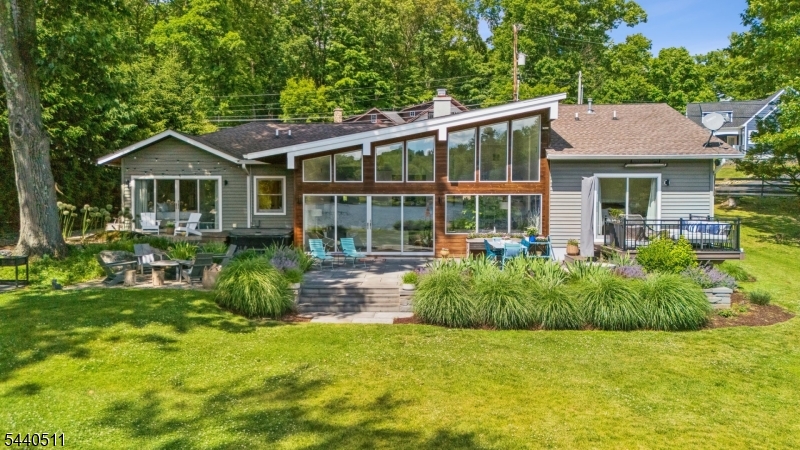 Birdsong. A breathtaking midcentury gem nestled in Upper Lake Mohawk's most coveted cove, set on nearly an acre of pristine lakefront. A property that announces itself with quiet confidence and rewards its next steward with something increasingly impossible to find: genuine peace.The magnificent great room soars with cathedral ceilings, hand-hewn wood beams, and a dramatic stone fireplace, anchored by a wall of glass framing the lake. Watch swans glide by while kingfishers streak across the cove. Warm bamboo flooring and central air run throughout the home. The chef's kitchen features a restaurant-grade gas range, sculptural mosaic backsplash, and flows naturally into a sun-drenched dining room.Two principal suites open onto private outdoor spaces. The first offers a spa-style en-suite bath with dual floating vanities, frameless glass shower, and a tucked-away hot tub on its own sheltered patio. The second, with a dedicated dressing room, overlooks a garden fountain from its south-facing deck. A third bedroom and full bath complete the home, finished with designer tile, floating vanities, and a deep soaking tub.Outside, blue stone terraces, all-season gardens, and a private dock with canoe await at the water's edge, where sunsets are the main event.Set in a private lake community just under 50 miles from NYC, with a Swiss Alpine-styled village, historic country club, three lakes, 12 beaches, walking trails, and a pool.Birdsong. Welcome Home!