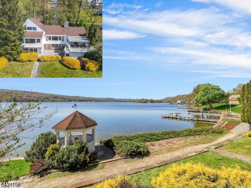 This is a rare opportunity to own one of Lake Mohawk's most coveted waterfront settings! Experience premier lakefront living in this original Crane-style home, within walking distance to the charming town in the heart of the lake community. Set on manicured grounds with breathtaking sunrises and sunsets and one of the most expansive lake views, this home showcases exceptional craftsmanship, soaring ceilings, and thoughtful design throughout. Just minutes walking distance to the highly sought-after LM Plaza, this 4BR, 3 BA residence blends comfort, elegance, and refined amenities. The main level features an open-concept living room with a wall of windows centered by a striking stone wood-burning fireplace, plus a separate sitting room. The updated kitchen with dining area opens to an expansive trex deck, perfect for entertaining or enjoying the serene lakeside setting. Add'l first-floor highlights include 2 bedrooms with a full bath. The primary suite can be on the main level or second floor, with additional bedrooms upstairs. The finished lower level offers a spacious den with a fireplace, walkout access to the level backyard, gazebo with the ability to add your own dock, a sunroom overlooking the lake, and a full bathroom. A two-car garage and abundant storage throughout complete this exceptional home. Whether a weekend retreat or full-time residence, embrace all that LM offers year-round swimming, boating, kayaking, beaches, clubhouse, tiki bar, outdoor dining, and more!