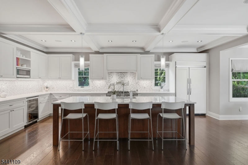 Nestled in the desirable Poet Section of Short Hills, this exceptional custom-built home blends timeless architecture with modern comfort across approximately 6,500 square feet. Built in 2013, the residence offers 6 bedrooms and 5.1 baths with an open, light-filled floor plan, soaring ceilings, hardwood floors and beautifully scaled rooms.At the heart of the home, the chef's kitchen features a large center island, breakfast bar, and spacious dining area, flowing into the expansive family room for everyday living and entertaining. Formal living and dining rooms, a private den, two fireplaces and a welcoming front porch add character and versatility to the main level.Upstairs, the primary suite serves as a peaceful retreat with a sitting room, oversized walk-in closet, spa-inspired bath and private balcony overlooking the adjacent golf course. Generously sized secondary bedrooms and a second-floor laundry room complete the upper level.The finished lower level offers exceptional flexibility with 10-foot ceilings, a recreation room, exercise room, den, full bath and abundant storage.Outside, the beautifully landscaped grounds feature a stunning in-ground salt water pool and spa, expansive patio and level backyard, creating a private setting for relaxing or entertaining. An oversized, on-grade two-car attached garage, multi-zone systems and an unbeatable location close to top-rated schools, parks, shopping and direct Manhattan transportation complete this outstanding offering.
