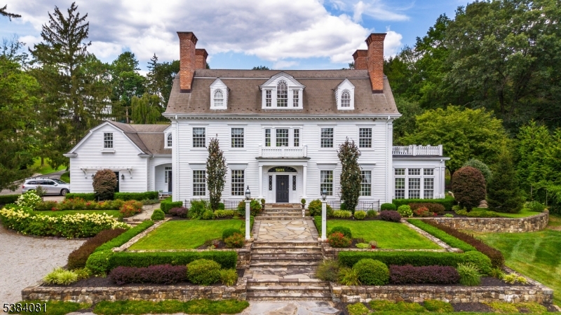 Entering the front gates, this Georgian Revival Colonial, newly built from the ground up in 2000, is sure to impress the most discriminating buyer. The architecture of this home embraces modern day living while staying true to classic early 19th century design. Situated on over 2.5 acres in historic Washington Valley, this stately property offers luxurious living without compromising aesthetics and historical architecture. With the finest appointments and attention to detail, classic old world features compliment new world amenities. Notable features include true-divided custom windows, hand cut wood floors sourced from property felled trees, nine layer crown moldings and extensive millwork, nine working masonry fireplaces and an impressive elliptical three-level staircase which is the heart of this home. Modern day amenities include a chefs kitchen with professional appliances, quartz counter tops, 10' center island and fully equipped butlers pantry. This home is perfect for entertaining year round with extensive blue stone patios featuring an outdoor kitchen, stone fireplace, three-tiered fountain, outdoor lighting and sound system and multiple seating areas for relaxing or dining al fresco. Mature landscaping, specimen flowering & fruit trees, stone walls, a fenced flower cutting garden and more complete the extensive grounds. An impressive one-of-a-kind estate property which must be seen to be truly appreciated and is just minutes to downtown Morristown and NYC direct.