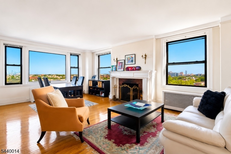 Experience timeless elegance and breathtaking NYC views in this exceptional corner residence at one of Forest Hill?s most prestigious pre-war buildings.Rich in architectural character, this sun-drenched home showcases an impressive wood-burning fireplace, gleaming hardwood floors, high beamed ceilings, Tiffany-inspired chandeliers, and solid wood doors adorned with original hardware. Expansive windows throughout frame panoramic views of the Manhattan skyline and surrounding cityscape, filling the home with natural light and creating an airy, inviting atmosphere.Designed with both comfort and privacy in mind, the thoughtfully laid-out floor plan places the primary and guest suites on opposite sides of the residence. The spacious updated kitchen features custom floor-to-ceiling wood cabinetry, abundant storage, and generous workspace, while the updated bathrooms offer modern tile finishes and contemporary style.Offering the storage capacity typically associated with a single-family home, the residence includes abundant closets, a private storage unit, and garage parking.Ideally located in Newark?s historic Forest Hill neighborhood, residents enjoy convenient access to Branch Brook Park, NYC transportation, major highways, NJPAC, Prudential Center, and the restaurants, entertainment, and cultural attractions of vibrant Downtown Newark.