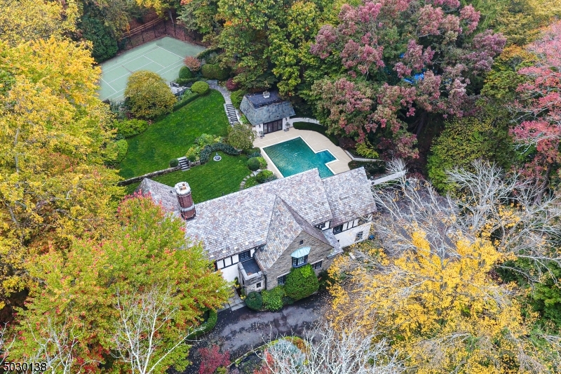 Travel up the majestic drive where "Terraces," a splendid English Style home, is nestled on well over an acre of tranquil property. Relax on its signature bluestone patio that overlooks rose gardens, the in-ground pool, hot tub, deluxe pool house, tennis court and manicured lawns. Inside, find a sunken living room with detailed plaster ceiling, light-filled dining room, library, updated kitchen and breathtaking family room. Original oak paneling, wrought iron banisters, leaded windows and inlaid floors are featured throughout. Upstairs, there are six exquisitely appointed bedrooms including the luxurious master suite. With rich history, Terraces offers a combination of livability & elegance while still in close proximity to downtown, NYC trains & top-rated Millburn schools -- the ideal Short Hills location!