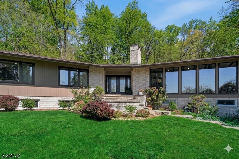 Tucked away on a private 0.57-acre wooded hillside, this 5 BR, 3 BA exceptional mid-century modern home offers a seamless blend of iconic design and resort-inspired living. The sun-filled interior features soaring vaulted ceilings with exposed beams and new 2026 European floor-to-ceiling windows and sliding doors that frame tranquil greenery. The open-concept living and dining areas flow effortlessly, anchored by rich wood accents and elegant architectural detailing. A chef's kitchen with Miele/SubZero appliances and radiant flooring, and newly updated designer bathrooms showcase stone composite tubs and premium finishes. The multi-tiered backyard is an entertainer's dream, complete with an in-ground pool, hot tub and built-in professional-grade outdoor kitchen, and secluded patios. A fully finished lower level with a sauna, recreation room, a full bathroom and 2 guest bedrooms completes this unparalleled sanctuary just moments from top-rated schools and the Mid-Town Direct train.